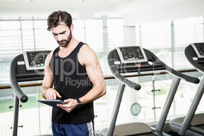 Serious man using tablet against treadmills