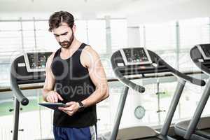 Serious man using tablet against treadmills