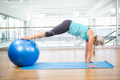 Fit blonde planking on mat with exercise ball