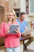 Happy wife using tablet while husband reading newspaper