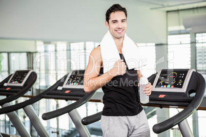 Smiling man on treadmill holding bottle of water