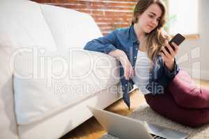 Pretty woman sitting on the floor using phone