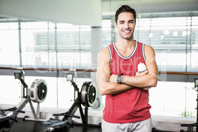 Smiling man with arms crossed holding bottle of water