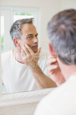 Handsome man looking at himself in the mirror