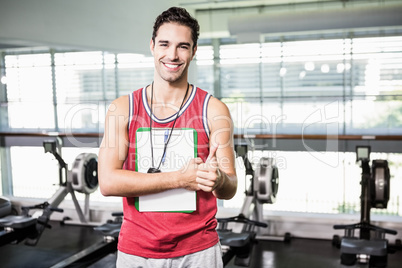 Smiling man standing with clipboard and stopwatch and showing th