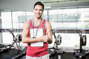 Smiling man standing with clipboard and stopwatch and showing th