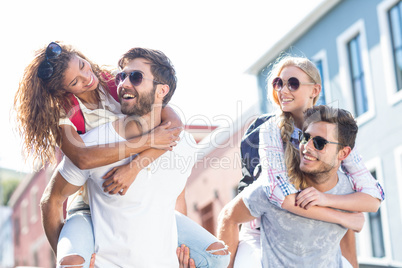 Hip men giving piggy back to their girlfriends