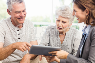 Businesswoman showing tablet to senior couple