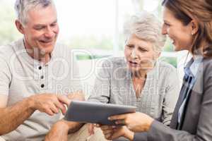 Businesswoman showing tablet to senior couple