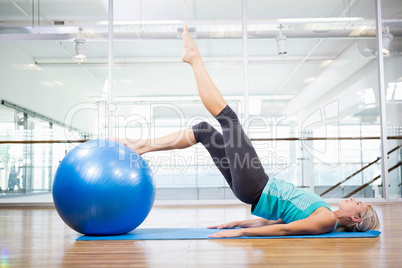 Fit blonde on mat exercising with fitness ball