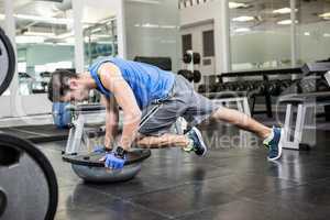 Muscular man exercising with bosu ball