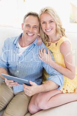 Happy couple using tablet on the sofa