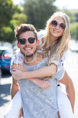 Hip man giving piggy back to his girlfriend