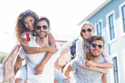 Hip men giving piggy back to their girlfriends