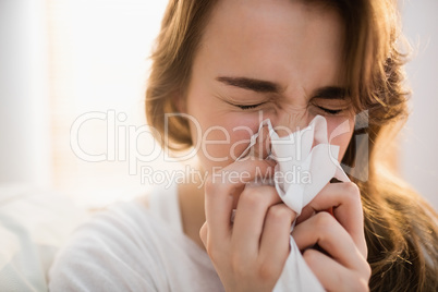 Woman blowing her nose on couch