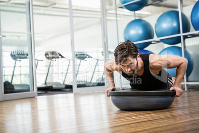 Serious man doing exercise with bosu ball