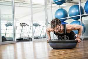 Serious man doing exercise with bosu ball