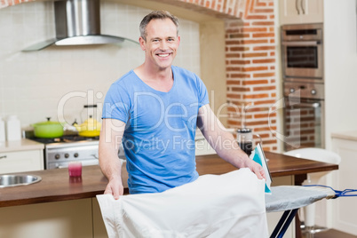 Handsome man ironing his clothes