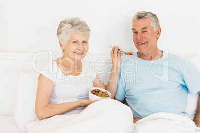 Happy senior woman feeding her husband