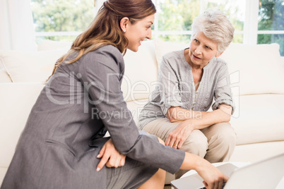 Smiling businesswoman showing documents to senior woman