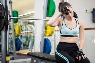 Tired woman sitting on barbell bench