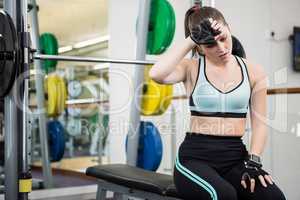 Tired woman sitting on barbell bench