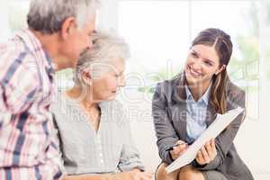 Smiling businesswoman showing documents to senior couple