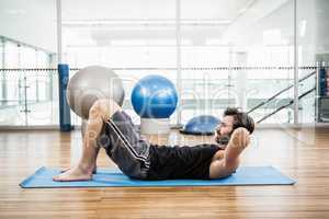 Muscular man doing abdominal on mat