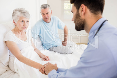 Handsome nurse holding hand of mature woman