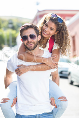 Hip man giving piggy back to his girlfriend