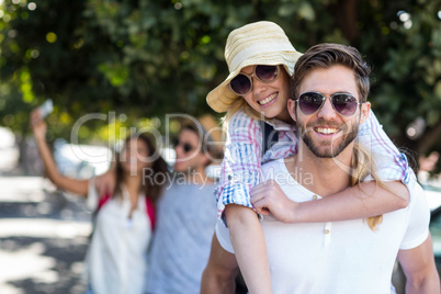 Hip man giving piggy back to his girlfriend