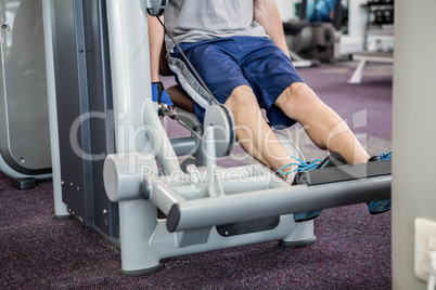 Focused man using weights machine for legs