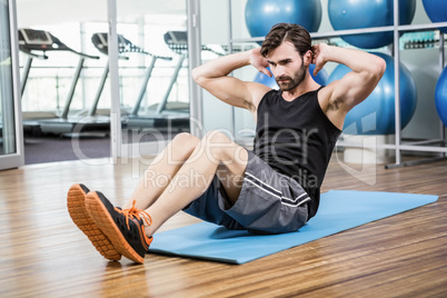 Serious man doing abdominal on the mat