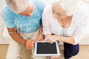 Focused senior couple using tablet