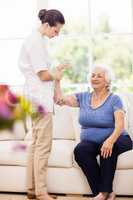 Physiotherapist taking care of sick elderly patient