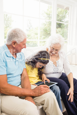 Grandparents using tablet with their granddaughter