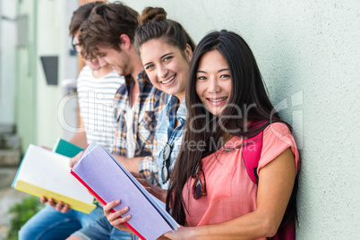 Hip friends leaning against wall and reading notebooks