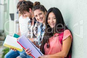 Hip friends leaning against wall and reading notebooks