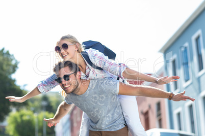 Hip man giving piggy back to his girlfriend