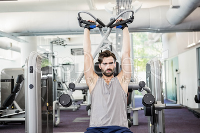 Focused man using weights machine for arms