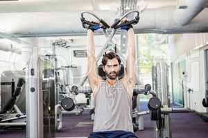 Focused man using weights machine for arms