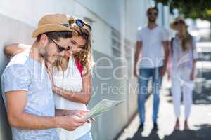 Hip couple checking map and leaning against wall