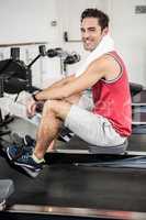 Muscular man on rowing machine smiling at the camera
