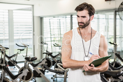 Serious trainer writing on clipboard