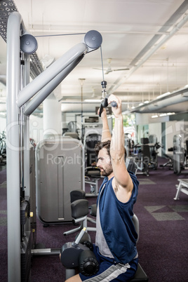 Focused man using weights machine for arms