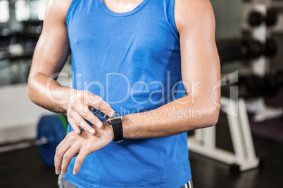 Mid section of handsome man using smartwatch