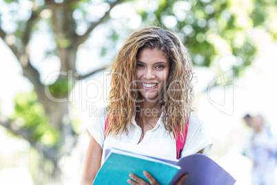 Hip woman holding notebook and smiling at the camera