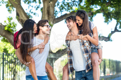 Hip men giving piggy back to their girlfriends