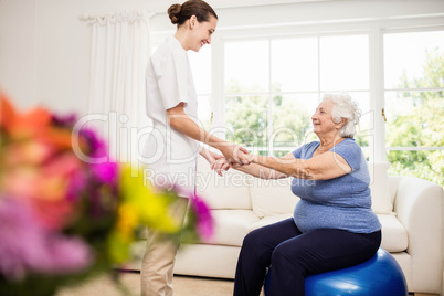 Physiotherapist taking care of sick elderly patient