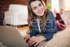 Pretty woman lying on the couch using laptop